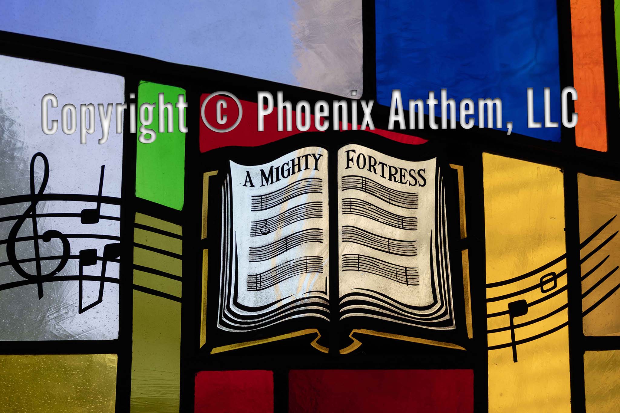Stained glass window depicting an open hymnal with the words ‘A Mighty Fortress’ surrounded by colorful red, blue, and gold panels at Trinity Lutheran Church in Sheboygan, Wisconsin.
