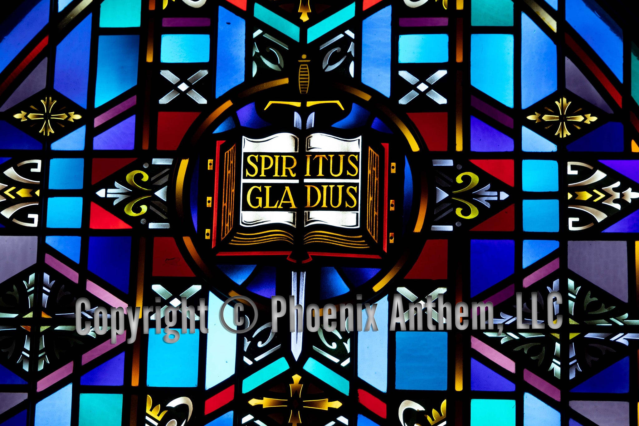 “Stained glass window depicting an open Bible with the words ‘Spiritus Gladius’ and a sword above it, surrounded by blue and red geometric panels at Trinity Lutheran Church in Sheboygan, Wisconsin.
