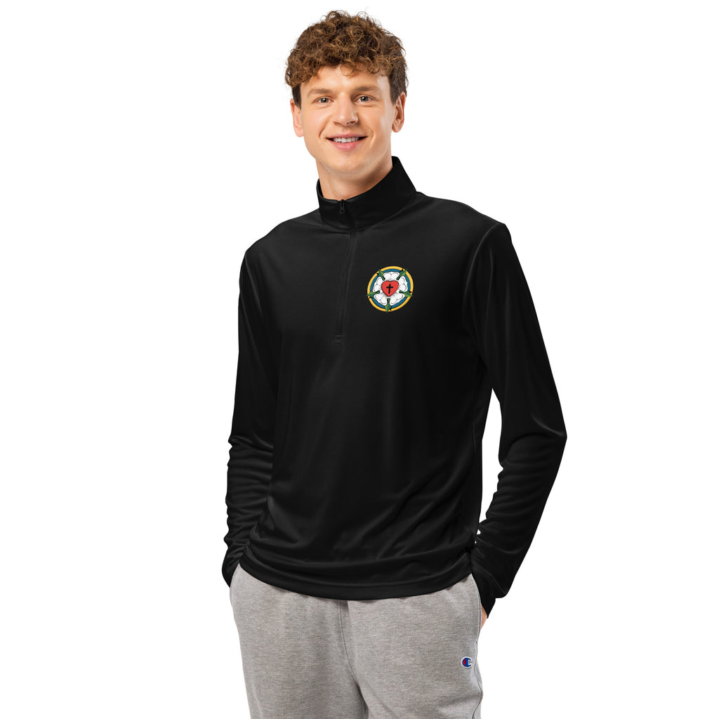 Front view of a man smiling while wearing the Sport-Tek ST357 lightweight quarter-zip pullover in black, featuring a minimalist embroidered Luther Rose seal on the left chest.