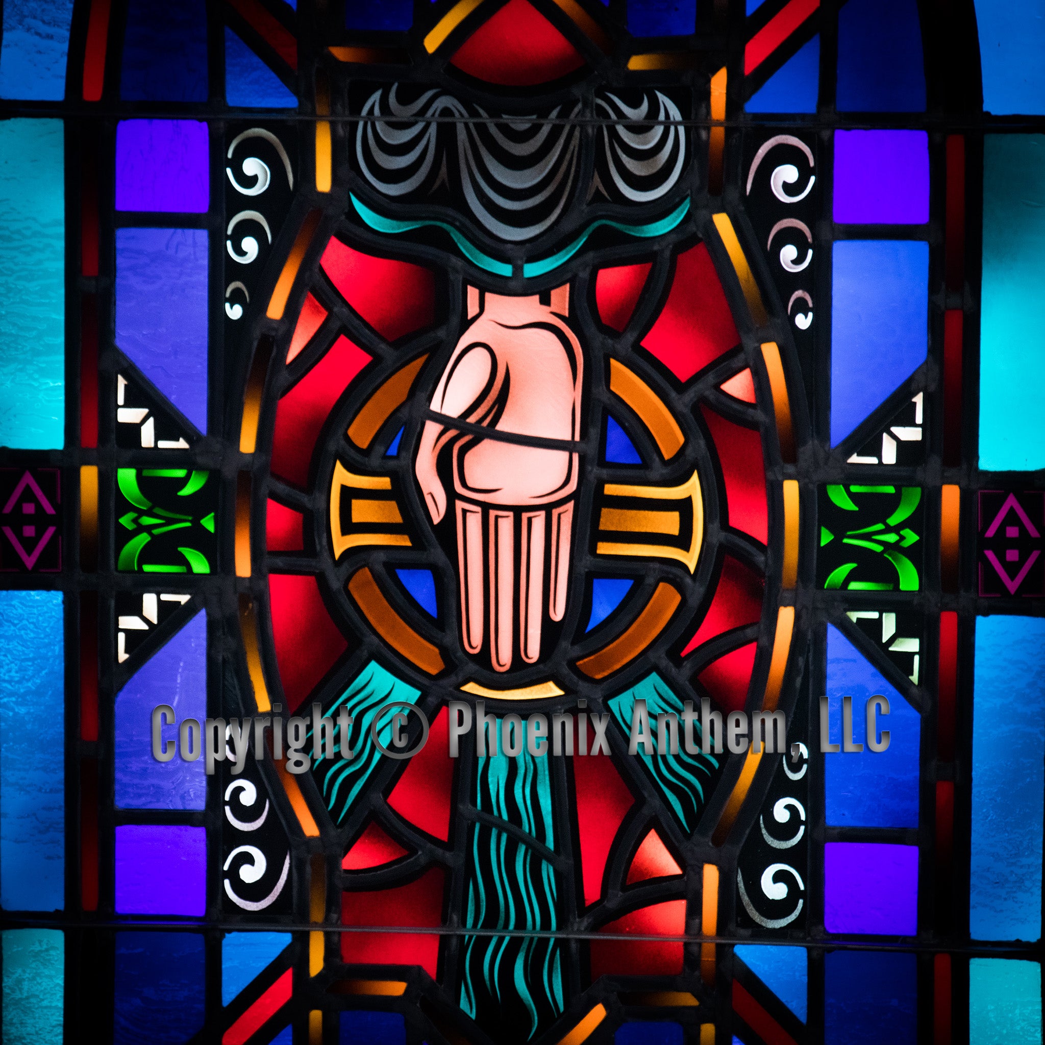 Stained glass window depicting the Hand of Providence descending in blessing, surrounded by red, blue, and green panels at Trinity Lutheran Church in Sheboygan, Wisconsin.