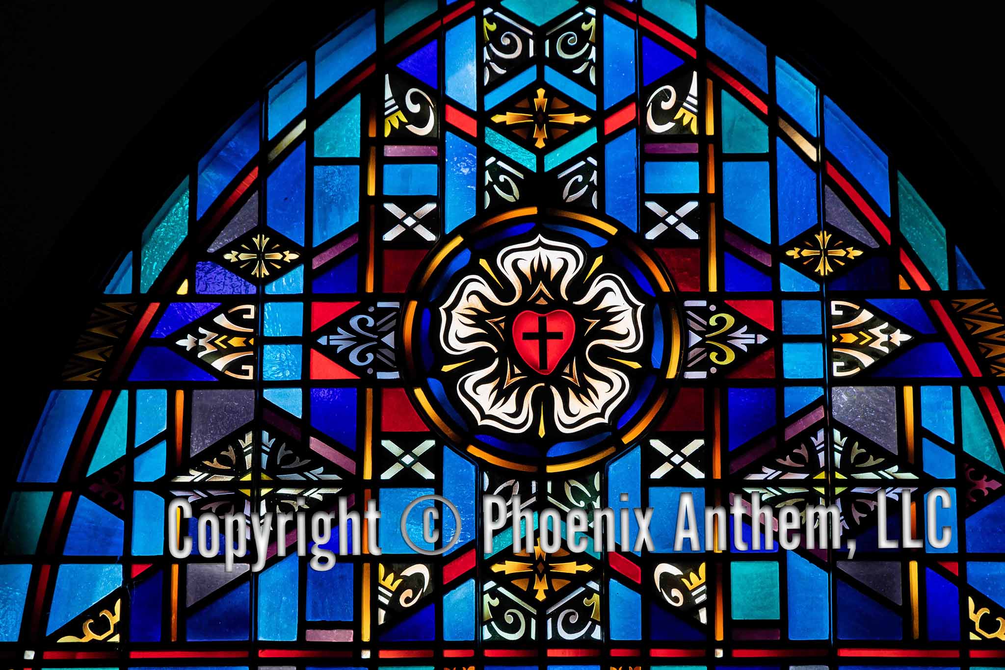 Stained glass window depicting the Luther Rose with a red heart and black cross surrounded by a white rose, blue field, and golden ring at Trinity Lutheran Church in Sheboygan, Wisconsin.
