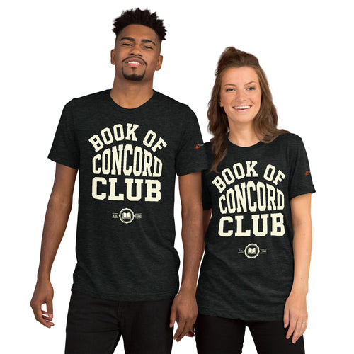 A man and woman modeling matching charcoal black tri-blend t-shirts featuring a collegiate "Book of Concord Club Est. 1580" graphic design. Premium Lutheran apparel and Christian theology clothing for men and women.