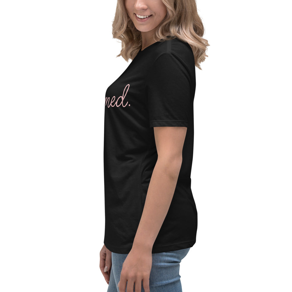 Side profile view from the left of a blonde woman wearing a black relaxed-fit Christian graphic tee with pink cursive writing. Modern religious clothing line from Phoenix Anthem.