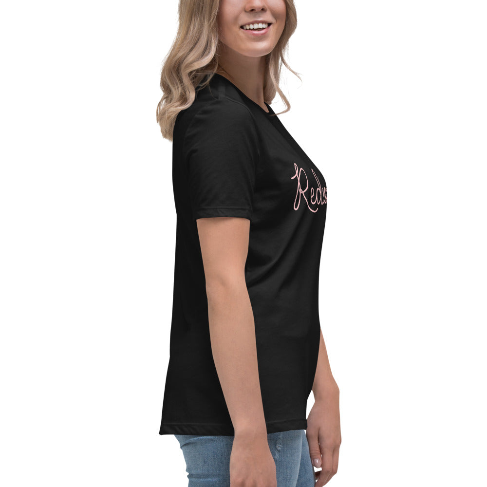 Side profile view from the right of a blonde woman wearing a black relaxed-fit Christian graphic tee featuring partial cursive text reading 'Redeemed'. Smart casual church outfit styling.