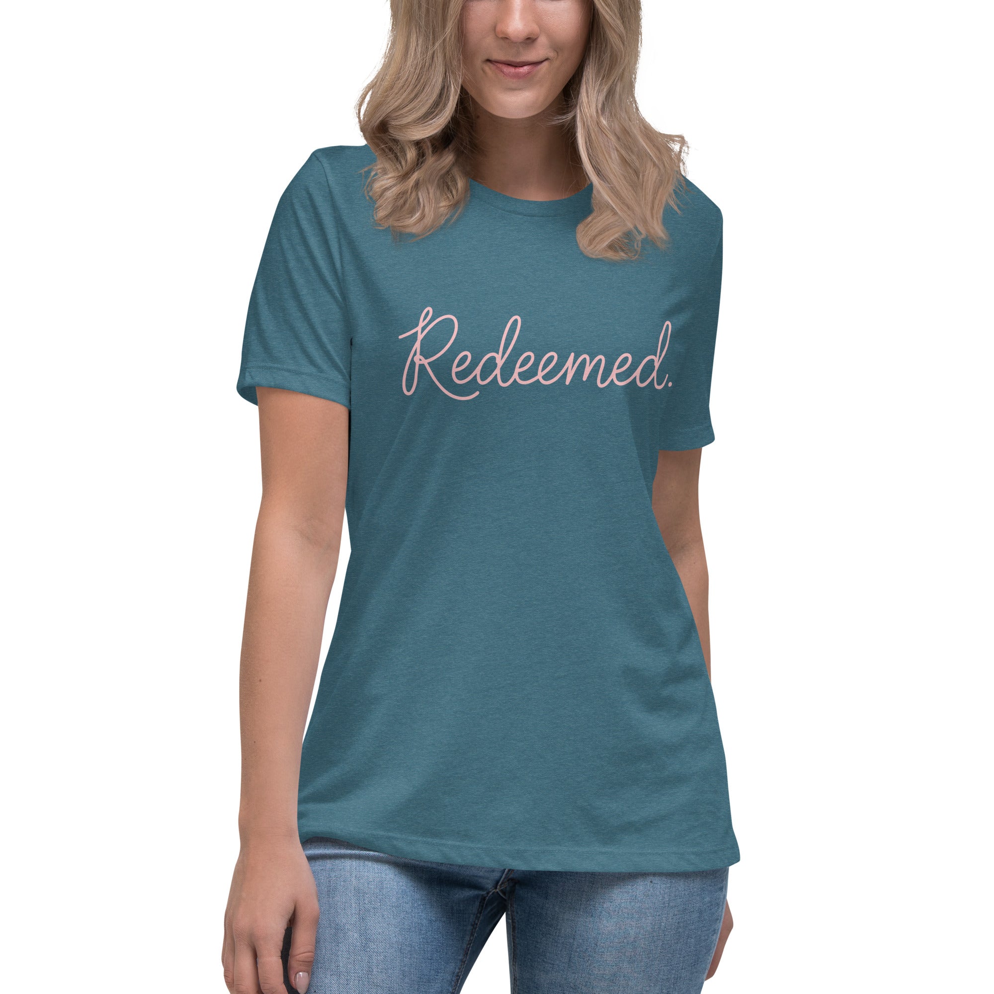 A blonde woman wearing a heather deep teal relaxed-fit Christian t-shirt featuring the word 'Redeemed.' in an elegant pink cursive font. Premium faith-based clothing for women from Phoenix Anthem.