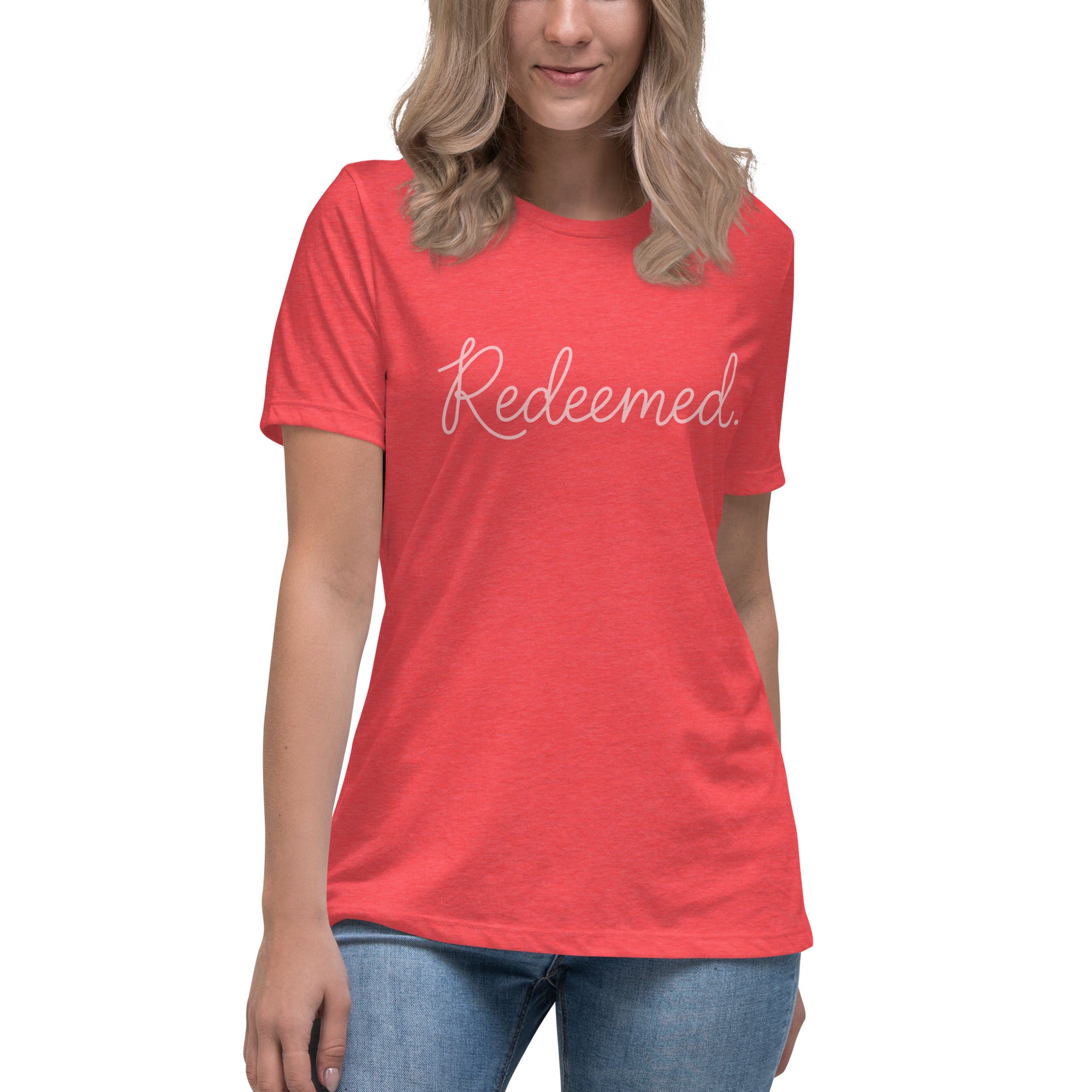 A blonde woman wearing a heather red relaxed-fit Christian t-shirt featuring the word 'Redeemed.' in an elegant pink cursive font. Premium faith-based clothing for women from Phoenix Anthem.