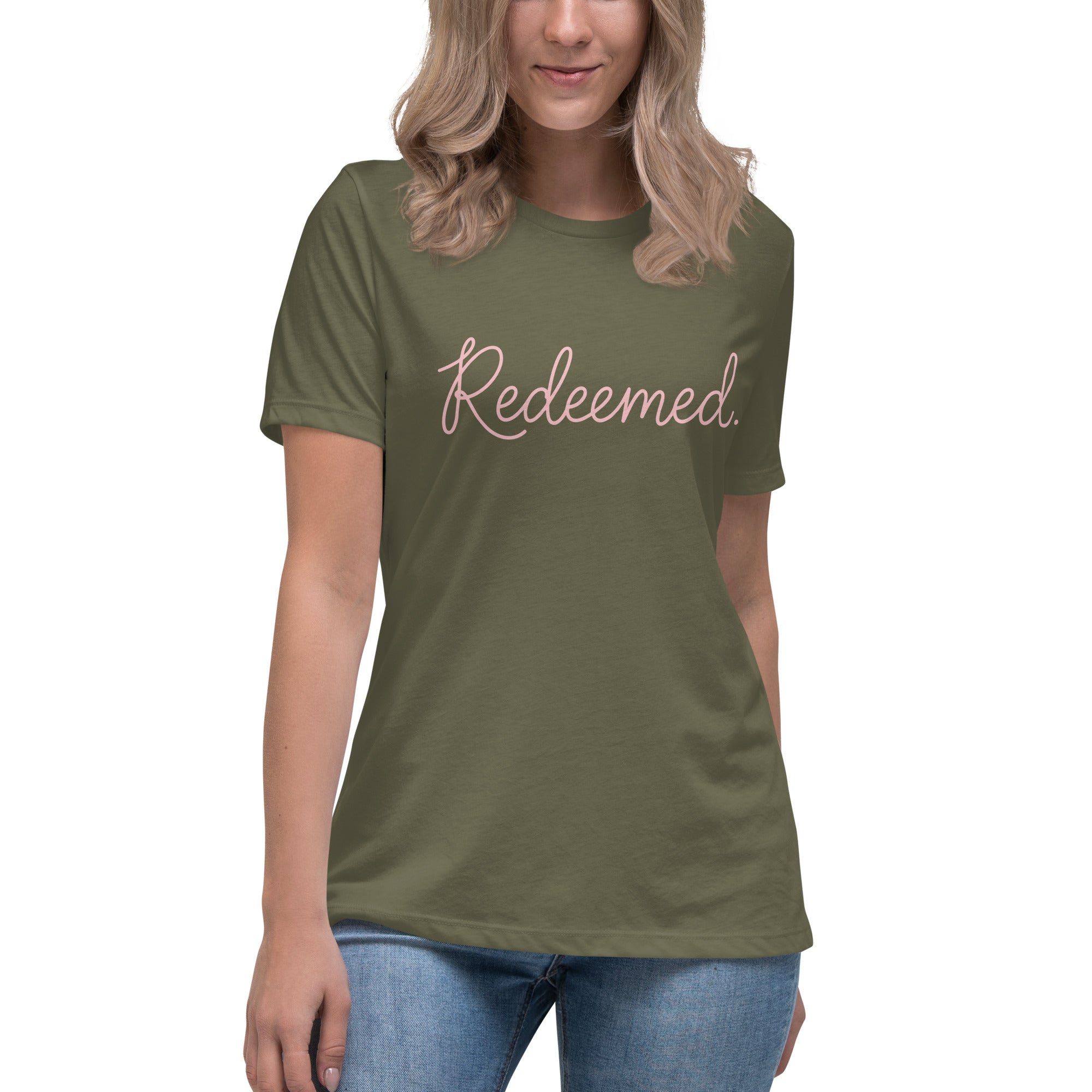 A blonde woman wearing a military green relaxed-fit Christian t-shirt featuring the word 'Redeemed.' in an elegant pink cursive font. Premium faith-based clothing for women from Phoenix Anthem.