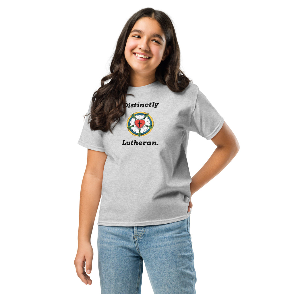 Smiling young girl wearing a sport grey children's Christian t-shirt with the 'Distinctly Lutheran' design and Luther Rose emblem. Faith-based youth apparel from Phoenix Anthem.